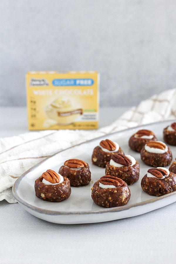 A stylish food photography shot of the White Chocolate Toffee Truffles on a serving platter, with the Simply Desserts Sugar-Free White Chocolate Pudding box subtly placed in the background