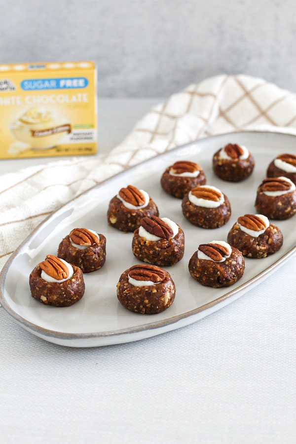 A plate of White Chocolate Toffee Truffles arranged neatly, each featuring a creamy white chocolate pudding center and a pecan half on top
