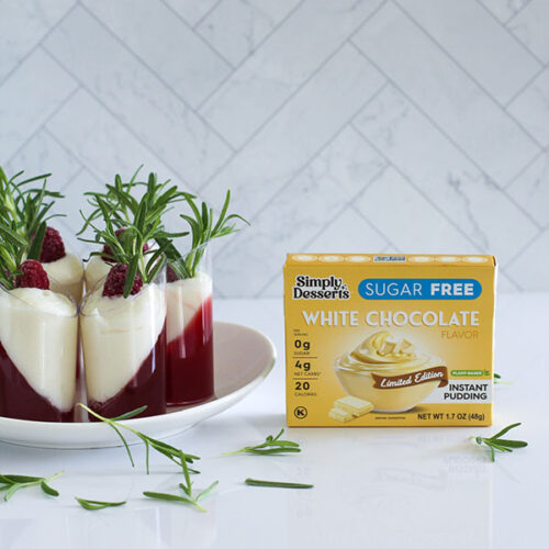 Simply Desserts Sugar Free White Chocolate Pudding box next to a plate of white chocolate cranberry passionfruit shooters, arranged with rosemary sprigs for decoration