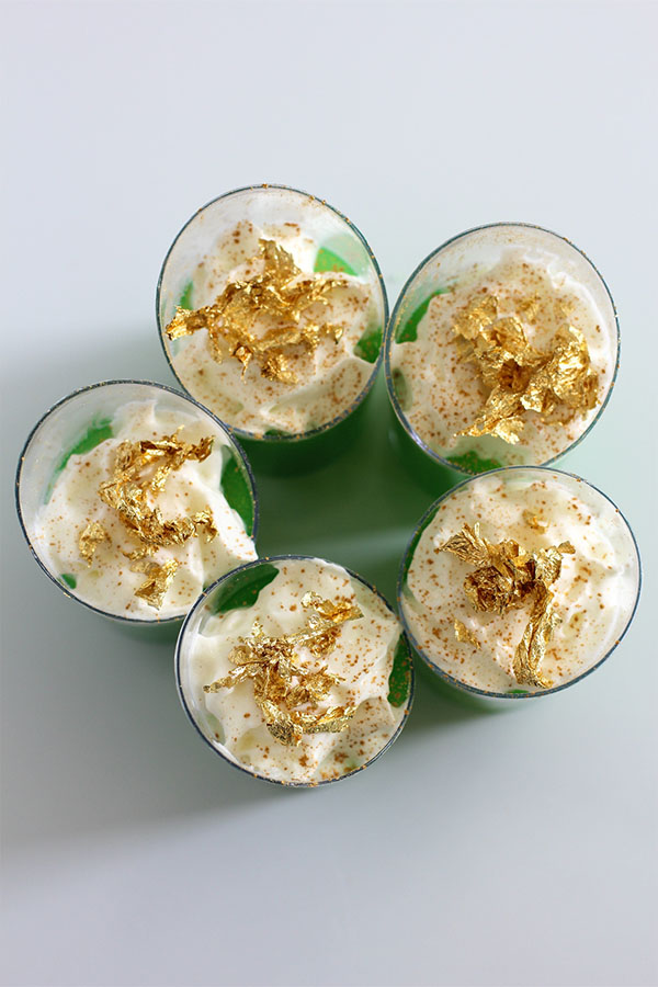 Irish Jello Shots - Top view of green Irish Jello shots with whipped cream and gold flakes