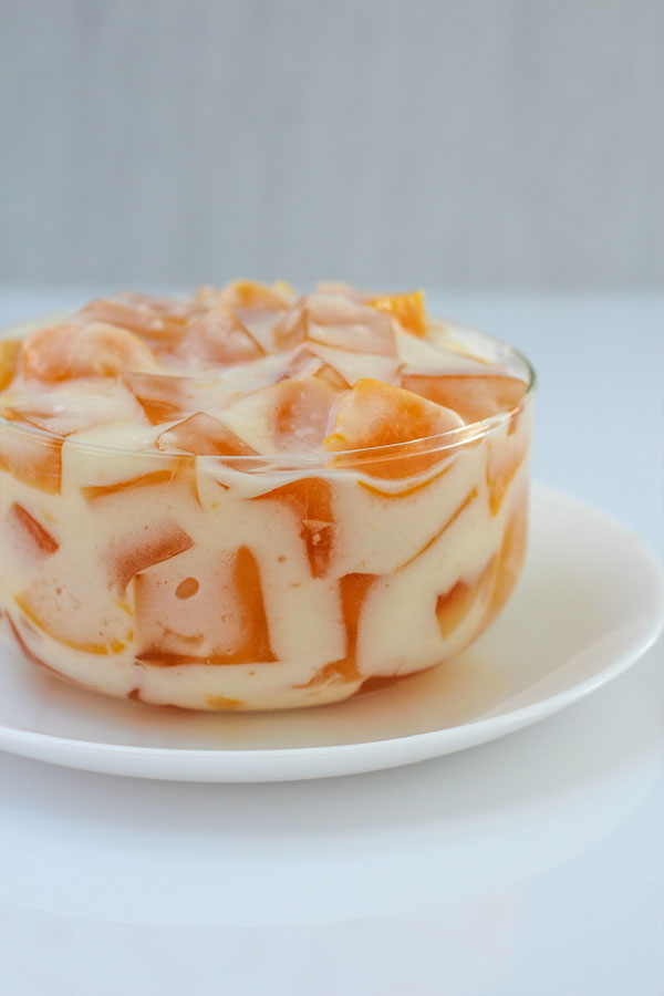 Side view of a glass bowl filled with peaches and cream jel salad