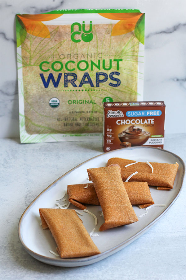 Plate of chocolate coconut ice cream wraps in front of Nuco Coconut Wraps and Simply Dessert Chocolate Pudding packaging