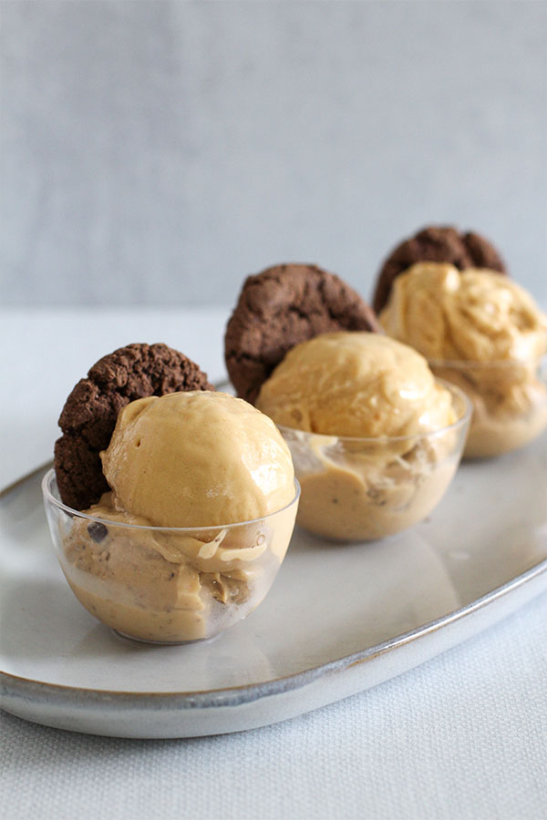glass cups filled with sugar free salted caramel ice cream made from simply desserts pudding, topped with mightylicious cookies, with product packs in the background