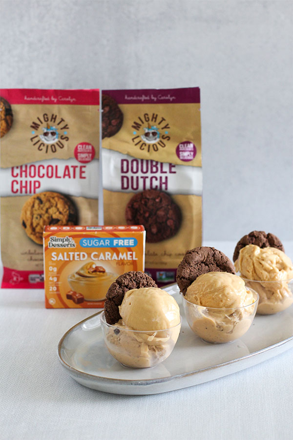 scoop of creamy salted caramel pudding ice cream served in a small clear cup with a mightylicious cookie, styled as a sugar free sundae