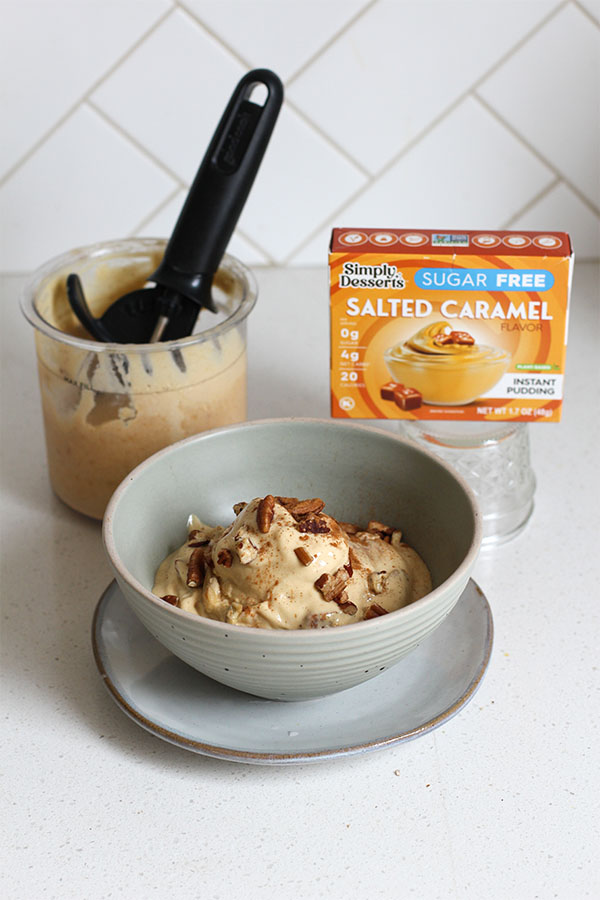 Bowl of salted caramel apple pecan ice cream with Ninja Creami pint and Simply Desserts pudding mix