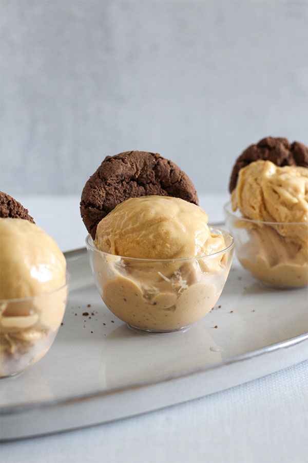 three mini glass dessert cups filled with salted caramel pudding ice cream made with simply desserts mix, each topped with a mightylicious cookie