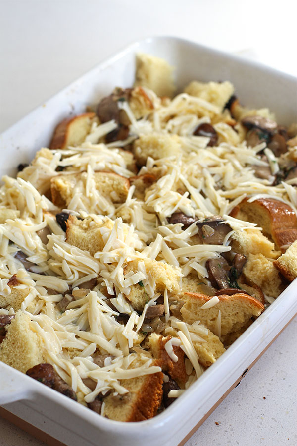 Savory bread pudding prepared with bread cubes, mushrooms, herbs and grated cheese before baking