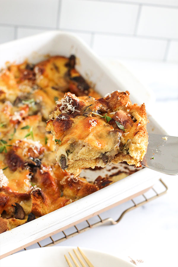 Cheesy savory bread pudding slice topped with herbs and parmesan