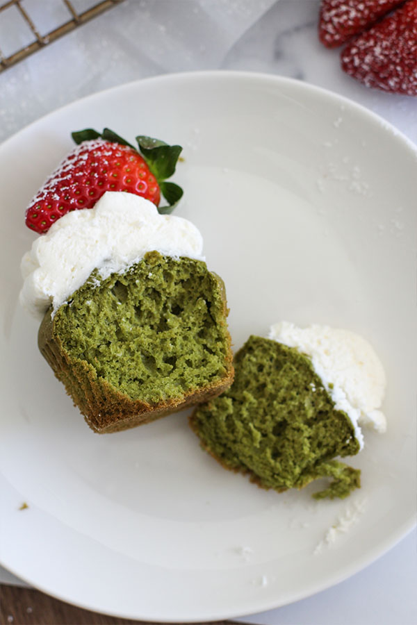 Sugar-free strawberry matcha cupcakes topped with white chocolate pudding frosting and fresh strawberries