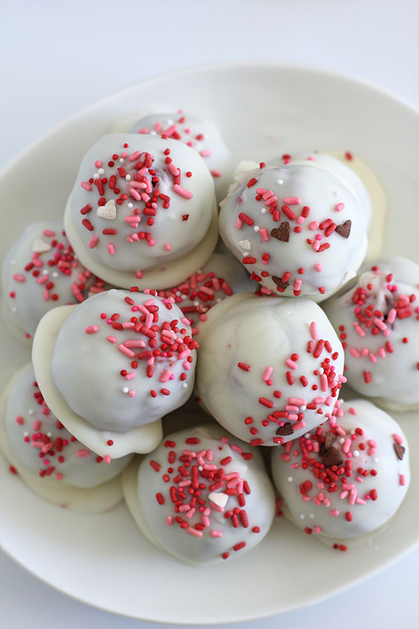 Red velvet cake pop balls dipped in white chocolate and topped with festive sprinkles