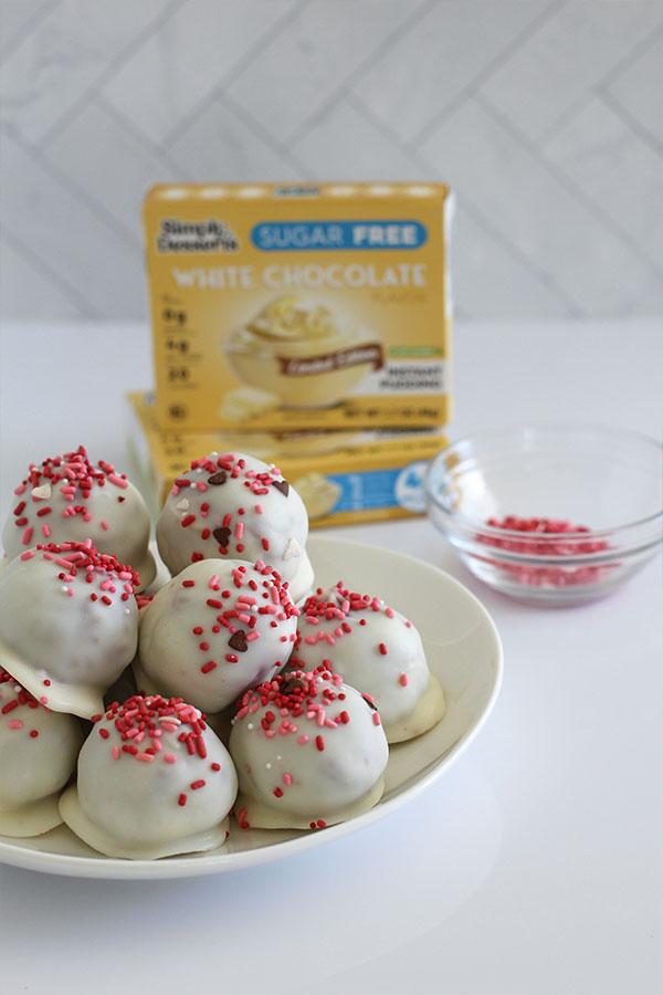 Red velvet cake pop balls dipped in white chocolate and topped with festive sprinkles