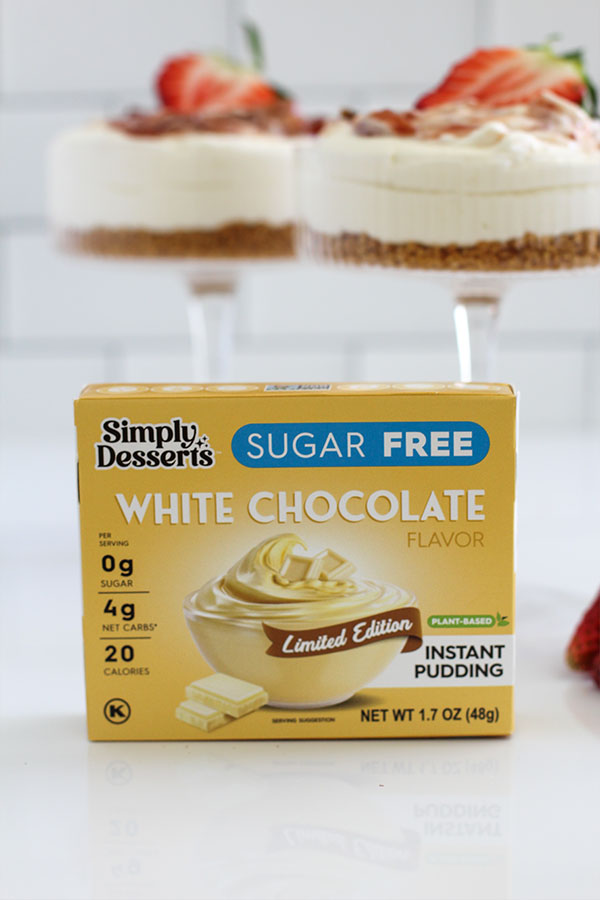 White Chocolate Cheesecake Cups with Strawberry Swirl close up front view with simply desserts white chocolate pudding box