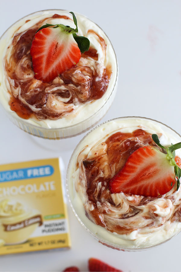 White chocolate cheesecake cups topped with strawberry swirl and fresh strawberries