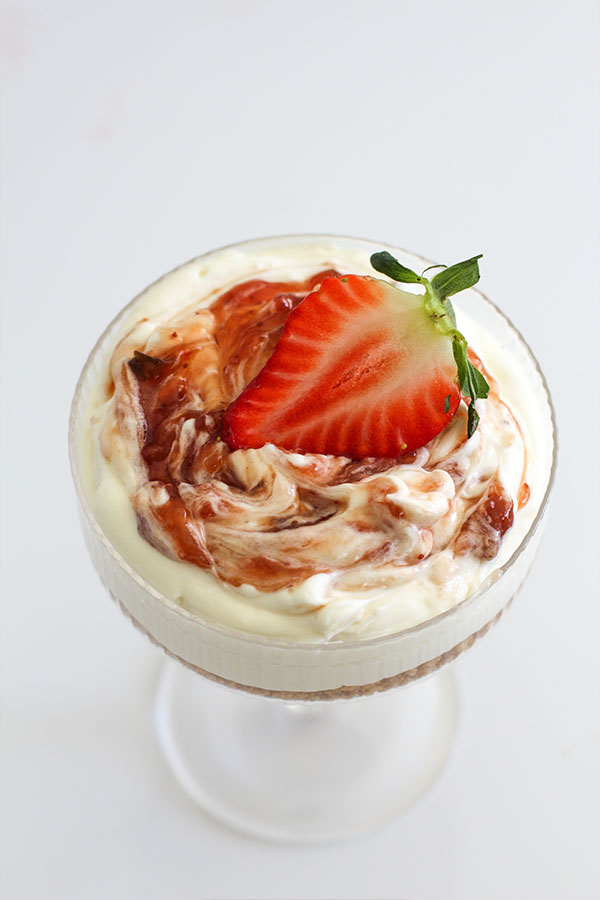 Close-up of a creamy white chocolate cheesecake cup with strawberry topping