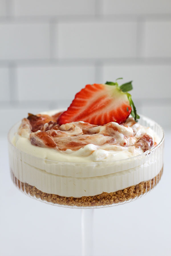 Layered white chocolate cheesecake cups with biscuit base and creamy filling