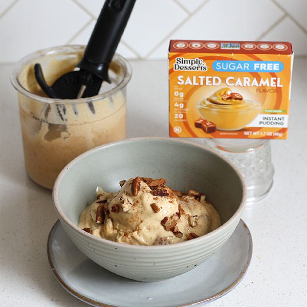 Bowl of salted caramel apple pecan ice cream with Ninja Creami pint and Simply Desserts pudding mix